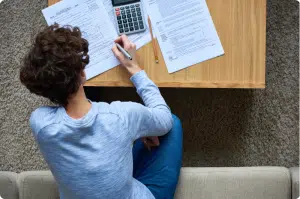 A man leaned over a table filling out tax forms.