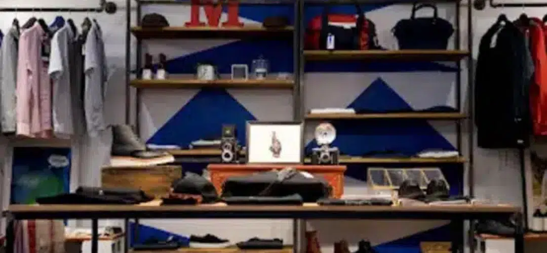 NEW BLOG HEADER Images Less than 200kb (7) A boutique retail display with industrial shelving holding an influencers' clothing on racks, bags, shoes, vintage cameras, and accessories against a bold blue and white geometric wall.