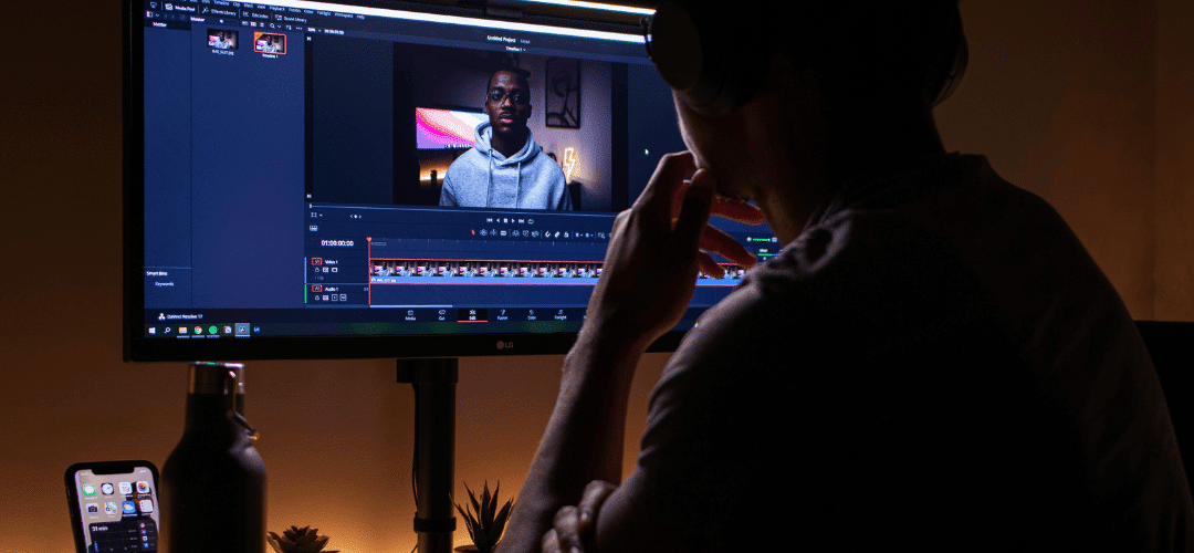 Tax Deductions for Content Creators (3) A person edits a video on a dark, dimly lit desk setup.