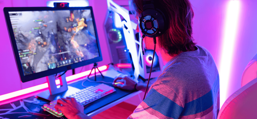 Twitch Streamer Taxes 5 Tips to Keep More of What You Earn (2) copy 3 Twitch streamer playing a PC game at a gaming setup with RGB lighting, wearing headphones, viewed from behind.