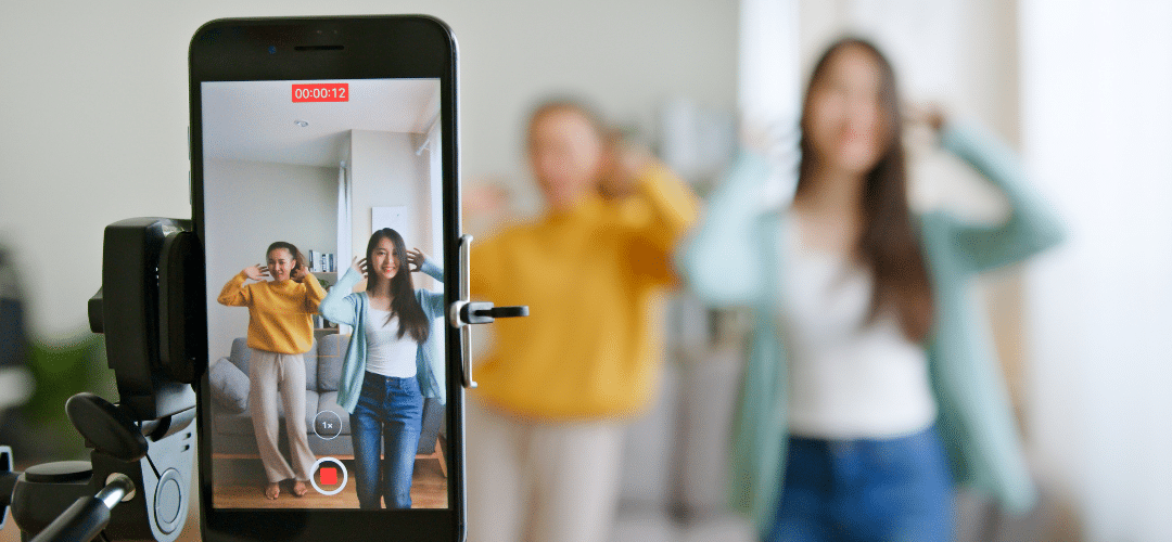 is tiktok getting banned in 2025 "A smartphone on a tripod records two women dancing and posing together in a living room, with the recording timer visible on screen and the subjects blurred in the background."